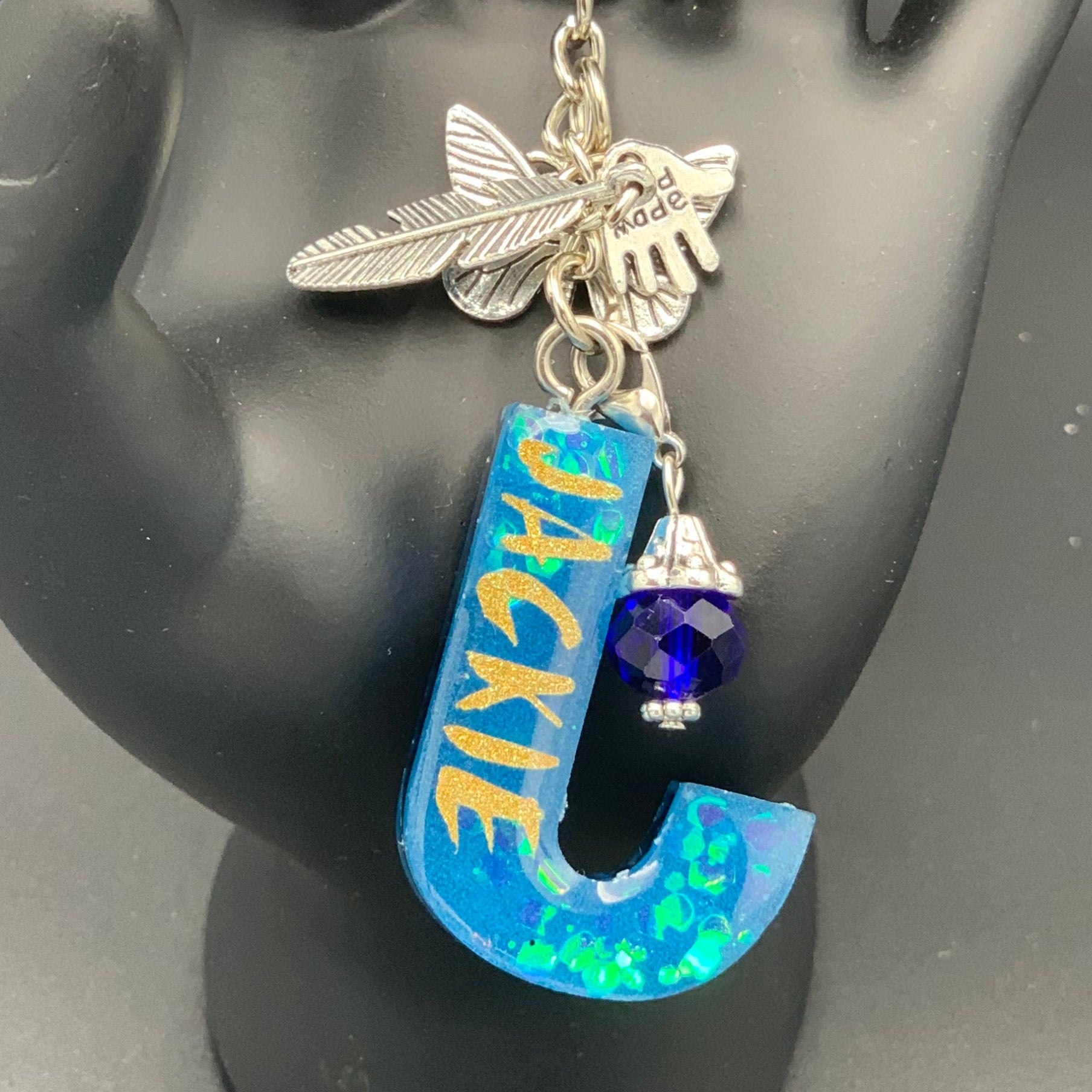 Keychain with charms on a black mannequin hand against a gray background