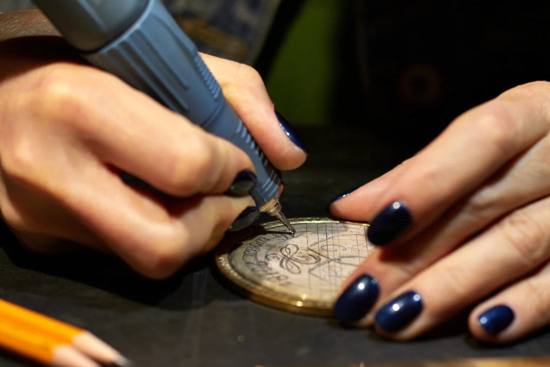 Artist engraving a custom art piece with a tool on a dark surface
